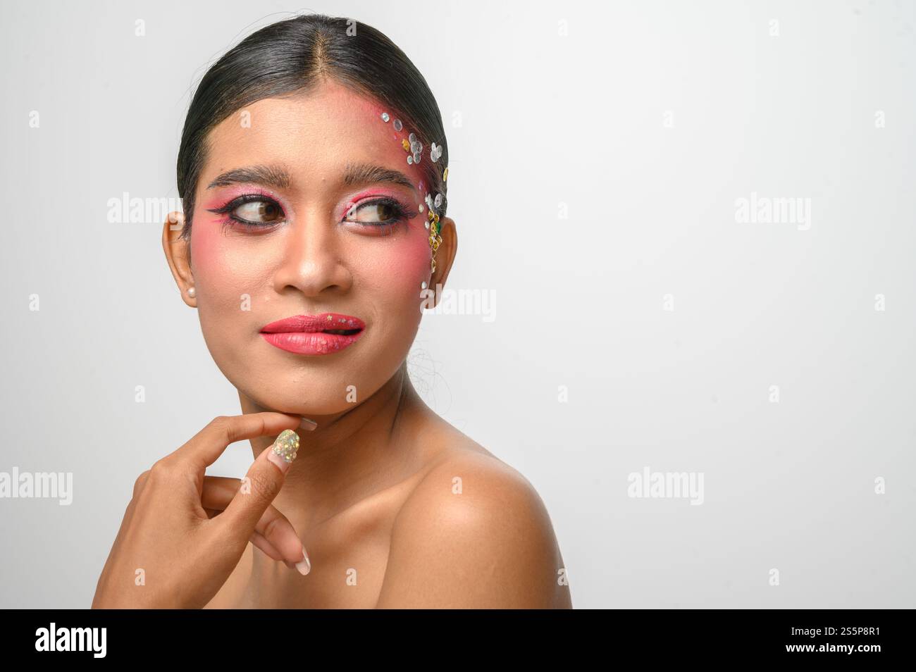Donna che indossa trucco e decorazioni rosa sul viso. Isolato su sfondo bianco Foto Stock