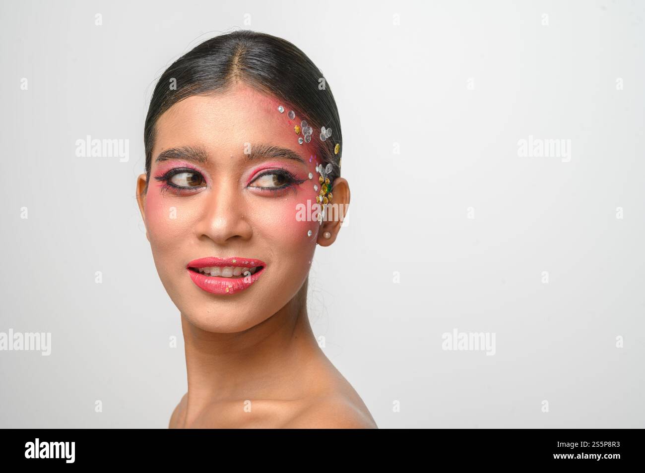 Donna che indossa trucco e decorazioni rosa sul viso. Isolato su sfondo bianco Foto Stock