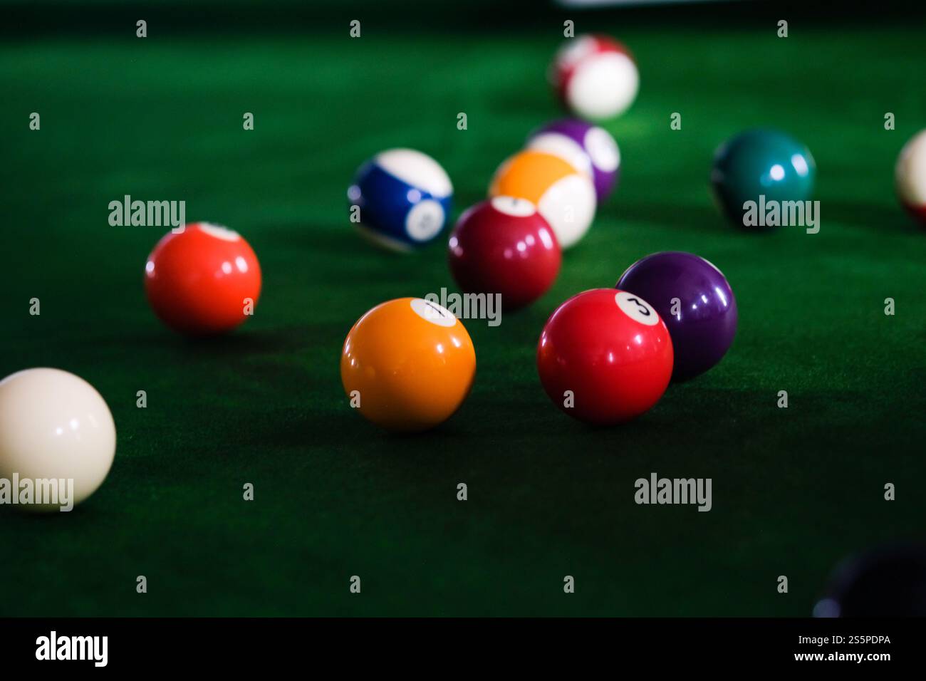 Mans mano e braccio cue giocano a biliardo o si preparano a sparare palle da biliardo su un tavolo da biliardo verde. Palline da biliardo colorate sul fregio verde Foto Stock
