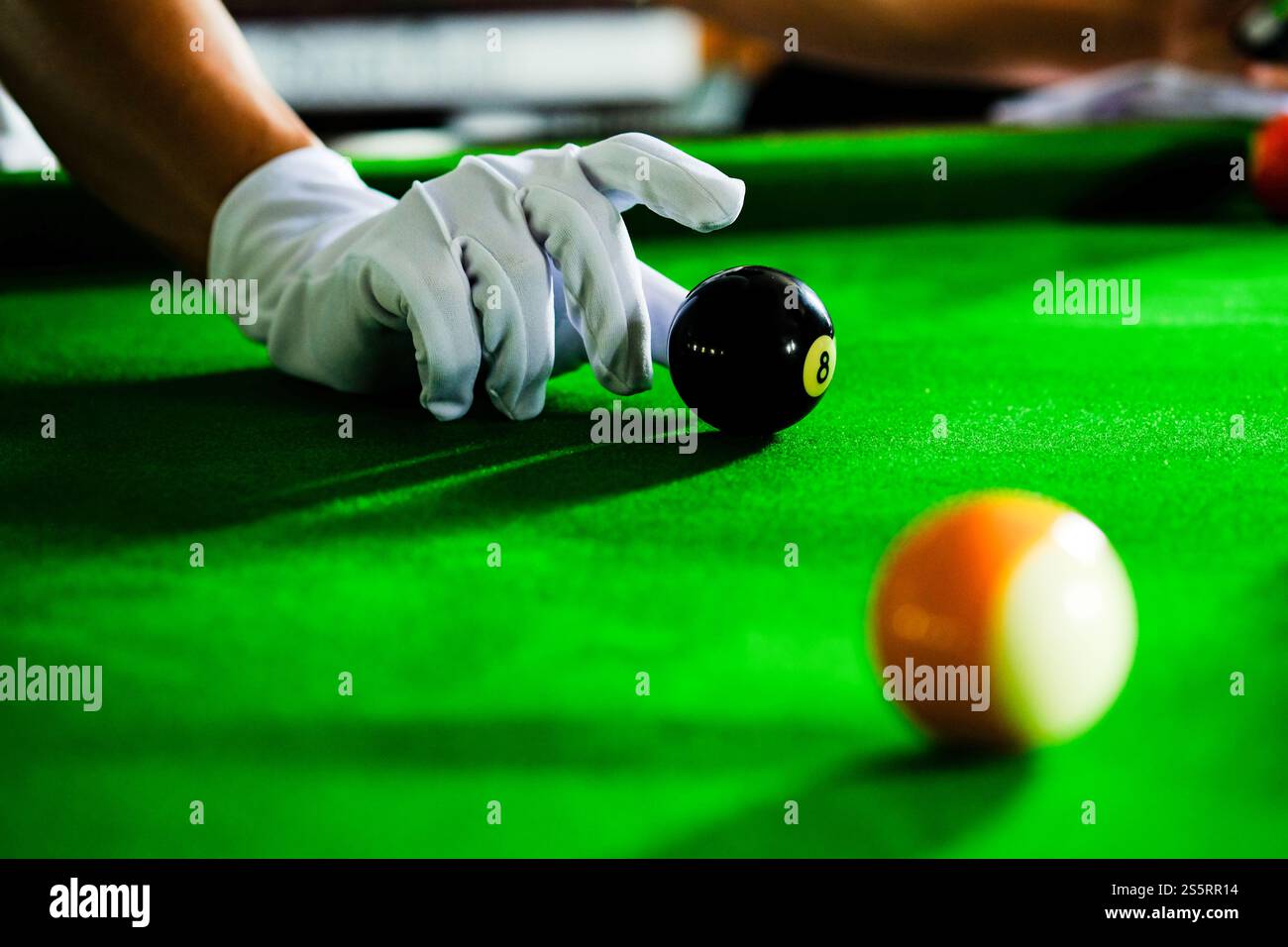 Mans mano e braccio cue giocano a biliardo o si preparano a sparare palle da biliardo su un tavolo da biliardo verde. Palline da biliardo colorate sul fregio verde Foto Stock