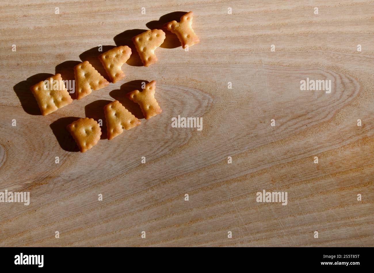 Buon giorno. Testo dai cracker salati come lettere inglesi stampate che giacciono su un tagliere di legno. Messaggio, fiancheggiato da lettere commestibili. Felice Foto Stock