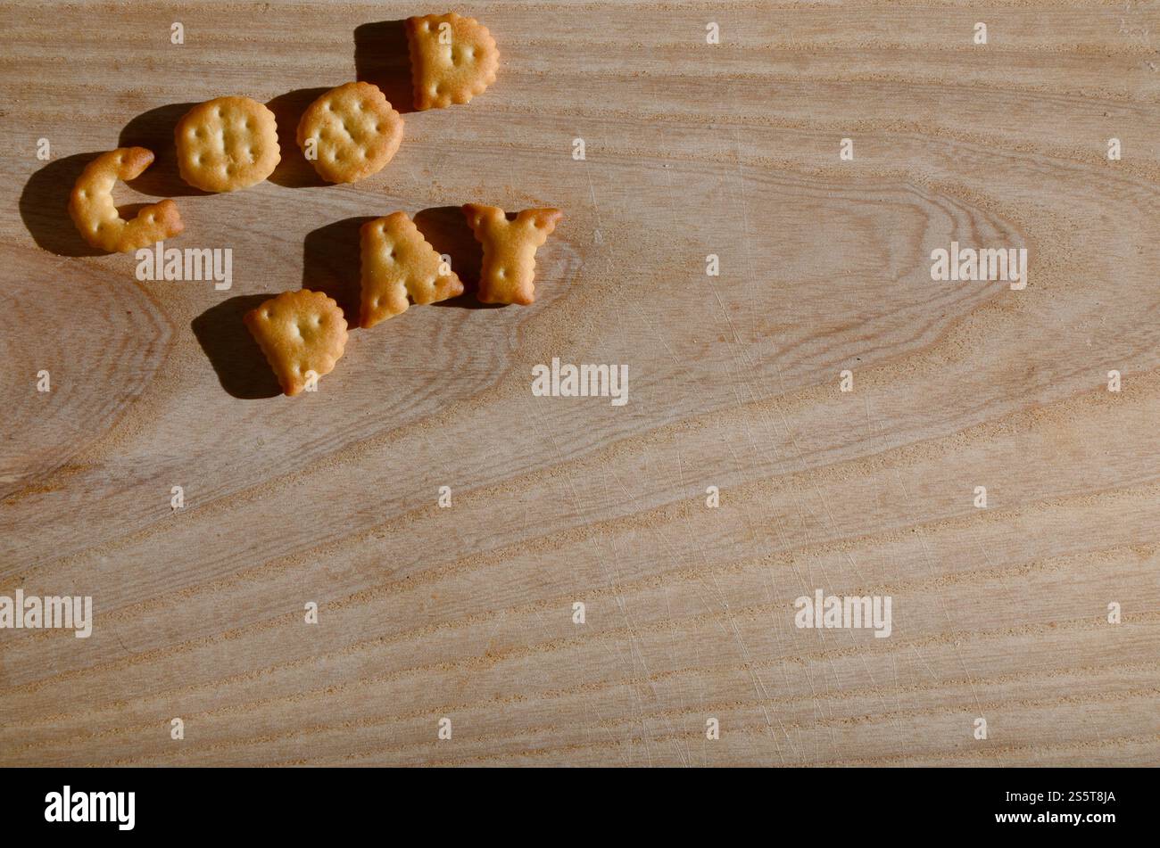 Buona giornata. Testo dai cracker salati come lettere inglesi stampate che giacciono su un tagliere di legno. Messaggio, fiancheggiato da lettere commestibili. Buona giornata. Foto Stock
