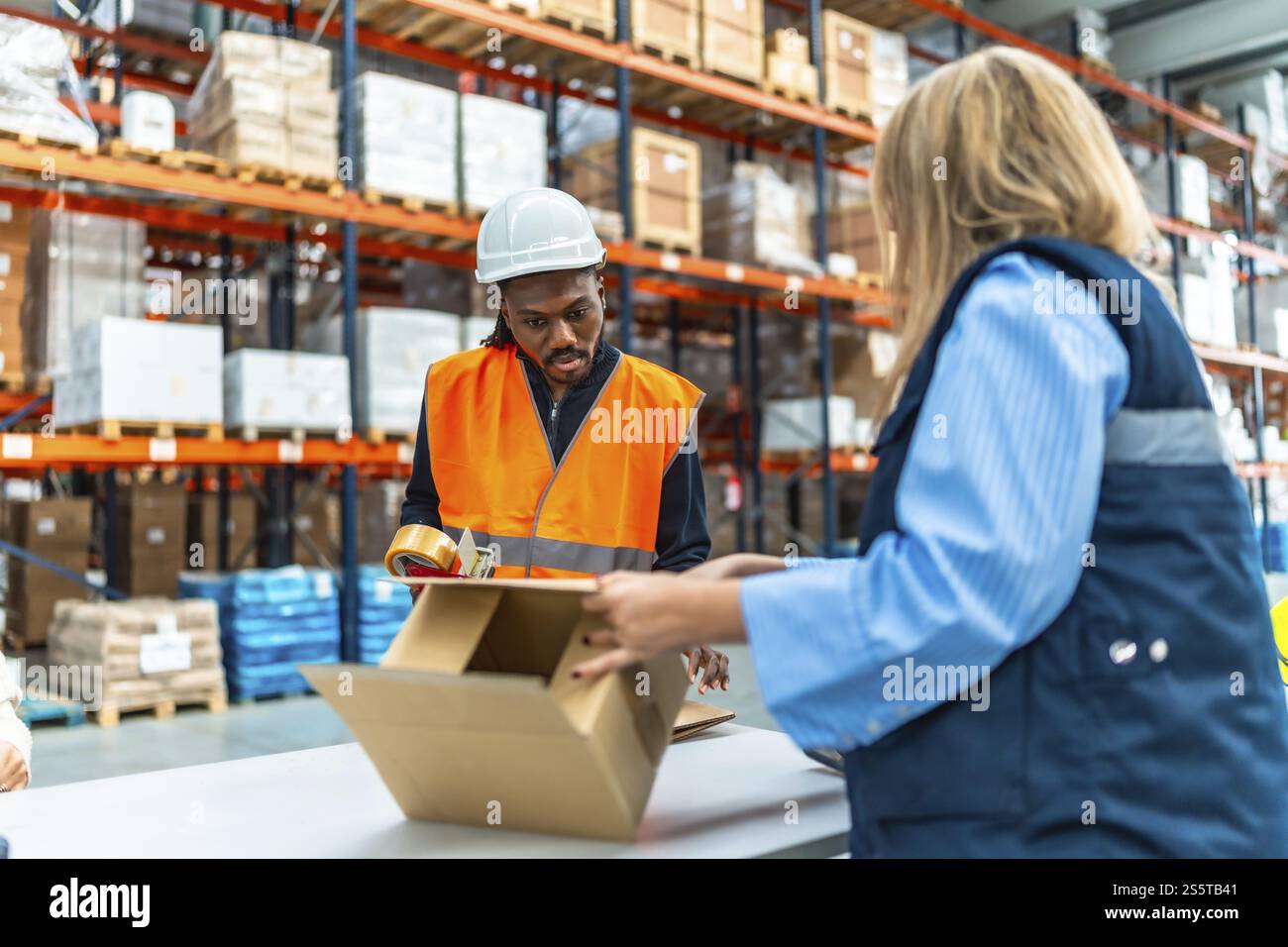 Lavoratori multietnici che preparano i pacchi per la consegna in un magazzino di distribuzione Foto Stock