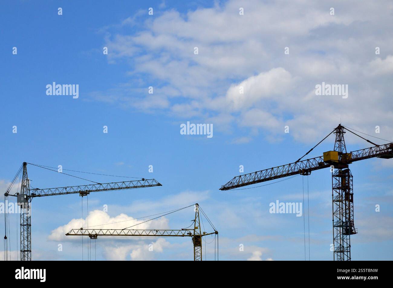 Alti e pesanti costruzione torri gru contro un cielo blu Foto Stock