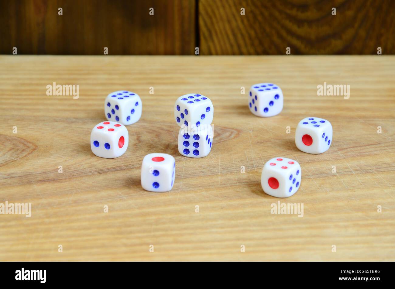 Alcuni dadi giacciono sulla superficie di legno naturale. Elementi per generare numeri da uno a sei sotto forma di punti dipinti sul lato di Foto Stock