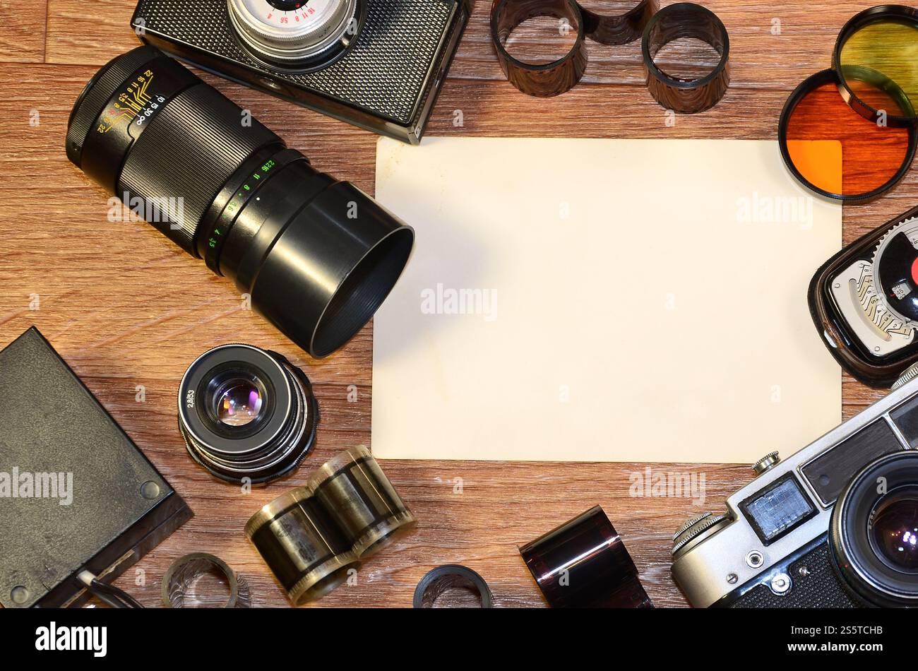 Fotocamera d'epoca, accessori fotografici e cornici vuote su un tavolo in legno. Natura morta con spazio di copia. Vista dall'alto. Immagine dai toni retrò in beige Foto Stock