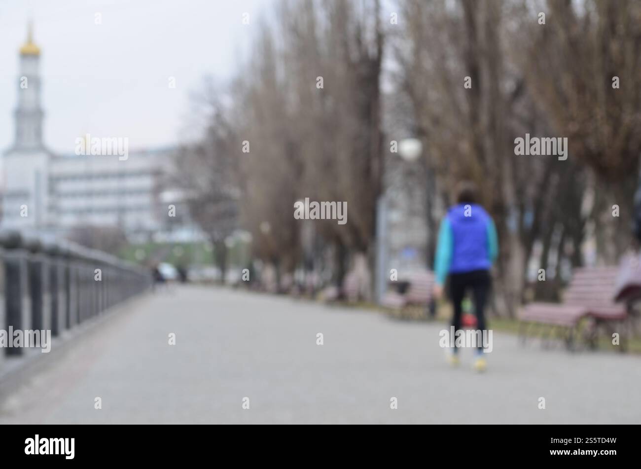 Paesaggio sfocato del parco primaverile vicino al lungomare. Strada davanti, decorata con alberi e una bassa recinzione dell'argine. Paesaggio sfocato di Foto Stock