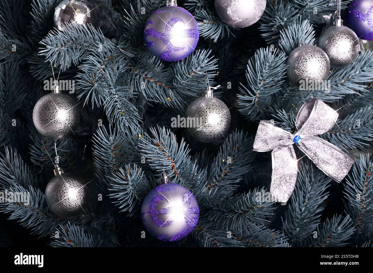 Foto dettagliata dell'albero di Natale decorato con regali, giocattoli sferici dai colori vivaci, nastri e ghirlande in primo piano. Sfondo astratto per Foto Stock