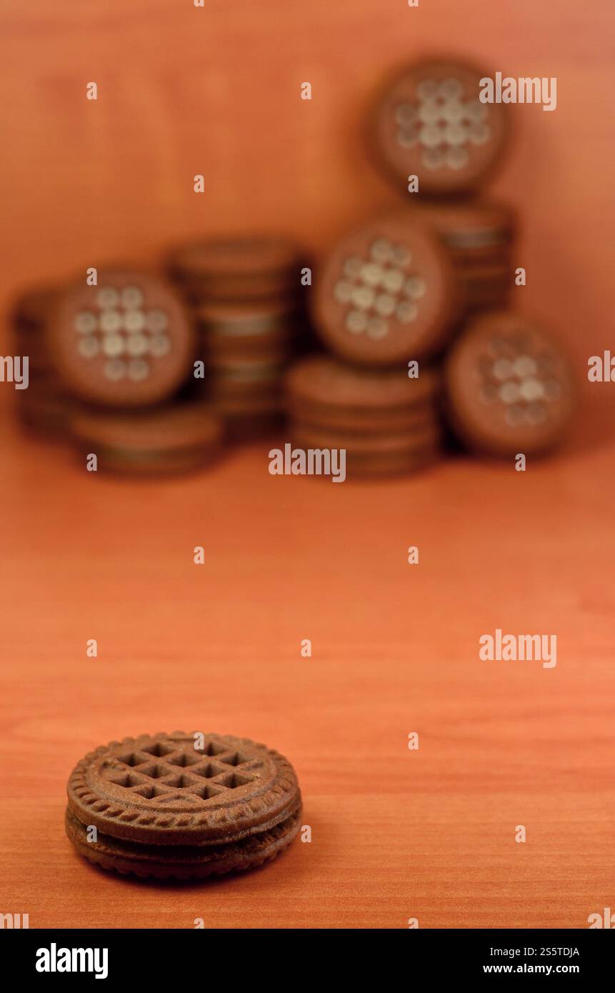 Panino al cioccolato, biscotti rotondi con ripieno di crema alla vaniglia su un tavolo di legno marrone con copyspace. Natura morta di biscotti dolci e gustosi con bianco Foto Stock