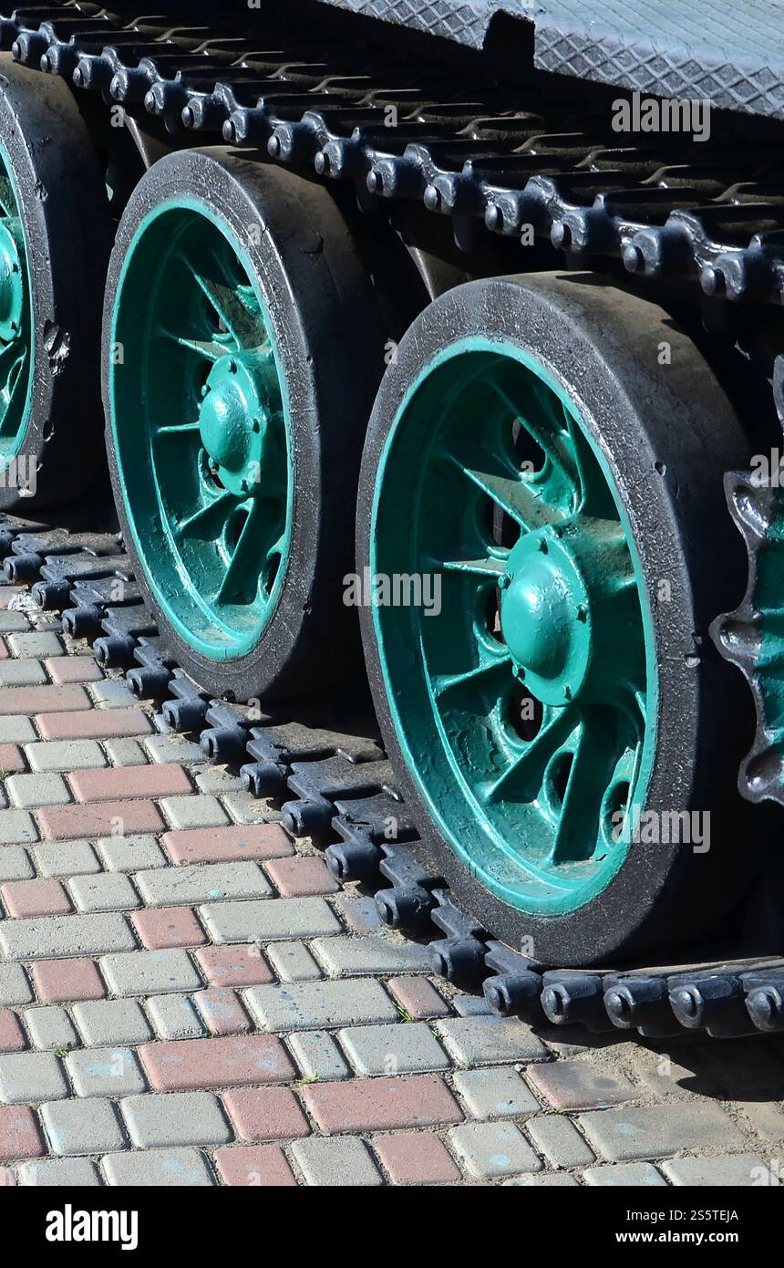 Un veicolo militare su cingoli sorge su un quadrato di pietre per pavimentazione. Foto di bruchi verde con ruote metalliche che li ruotano Foto Stock