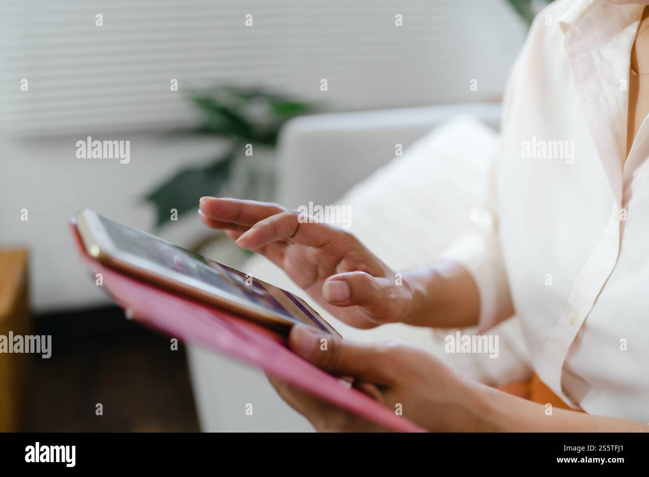 Donna asiatica di mezza età che tiene il telefono cellulare. donna anziana con smartphone. donna anziana che utilizza lo smartphone a casa con il concetto di tecnologia. Foto Stock