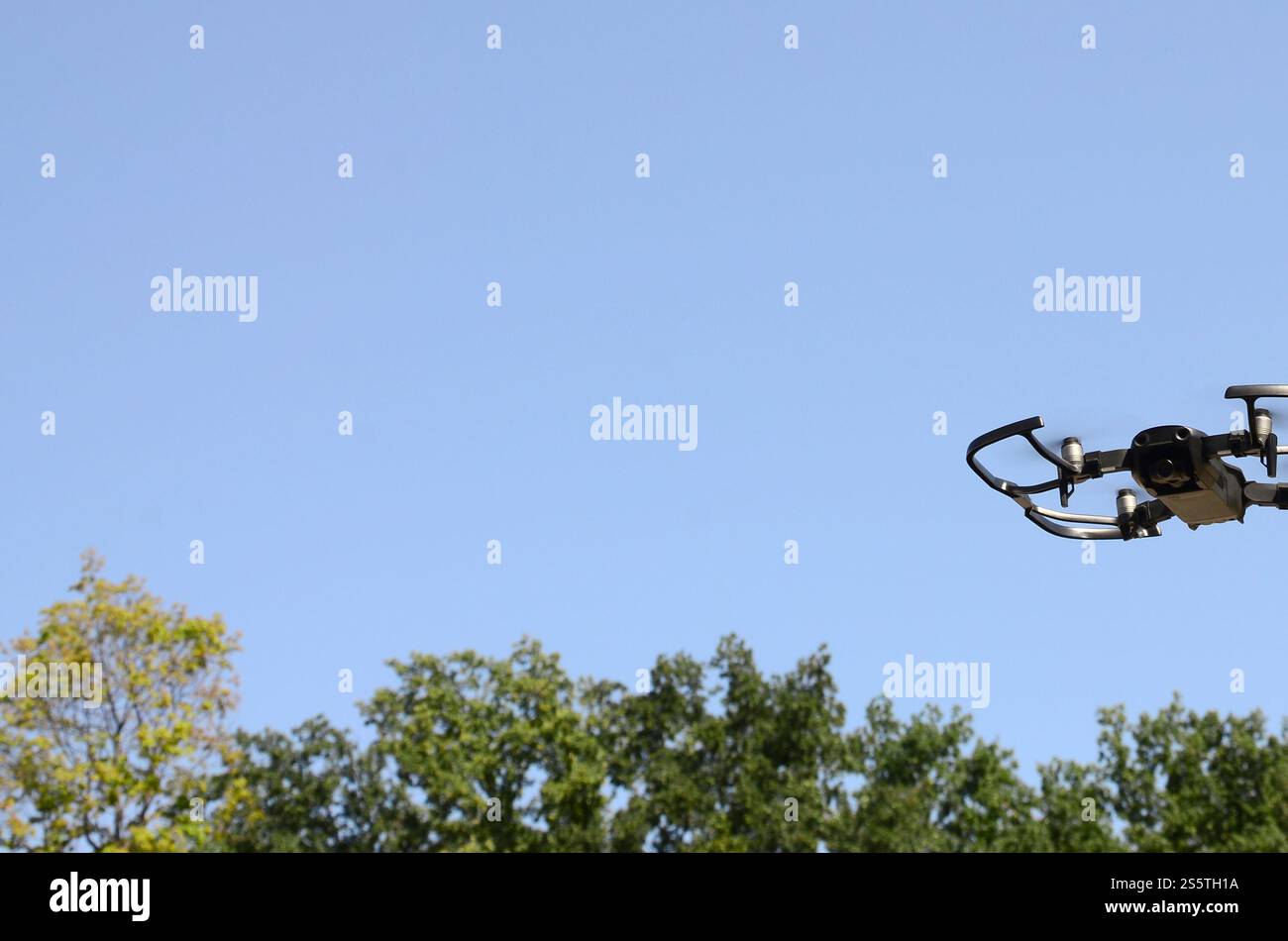 Drone con fotocamera decolla dalla terraferma e vola per scattare foto aeree al tramonto davanti agli alberi. Drone con fotocamera decollo da Foto Stock