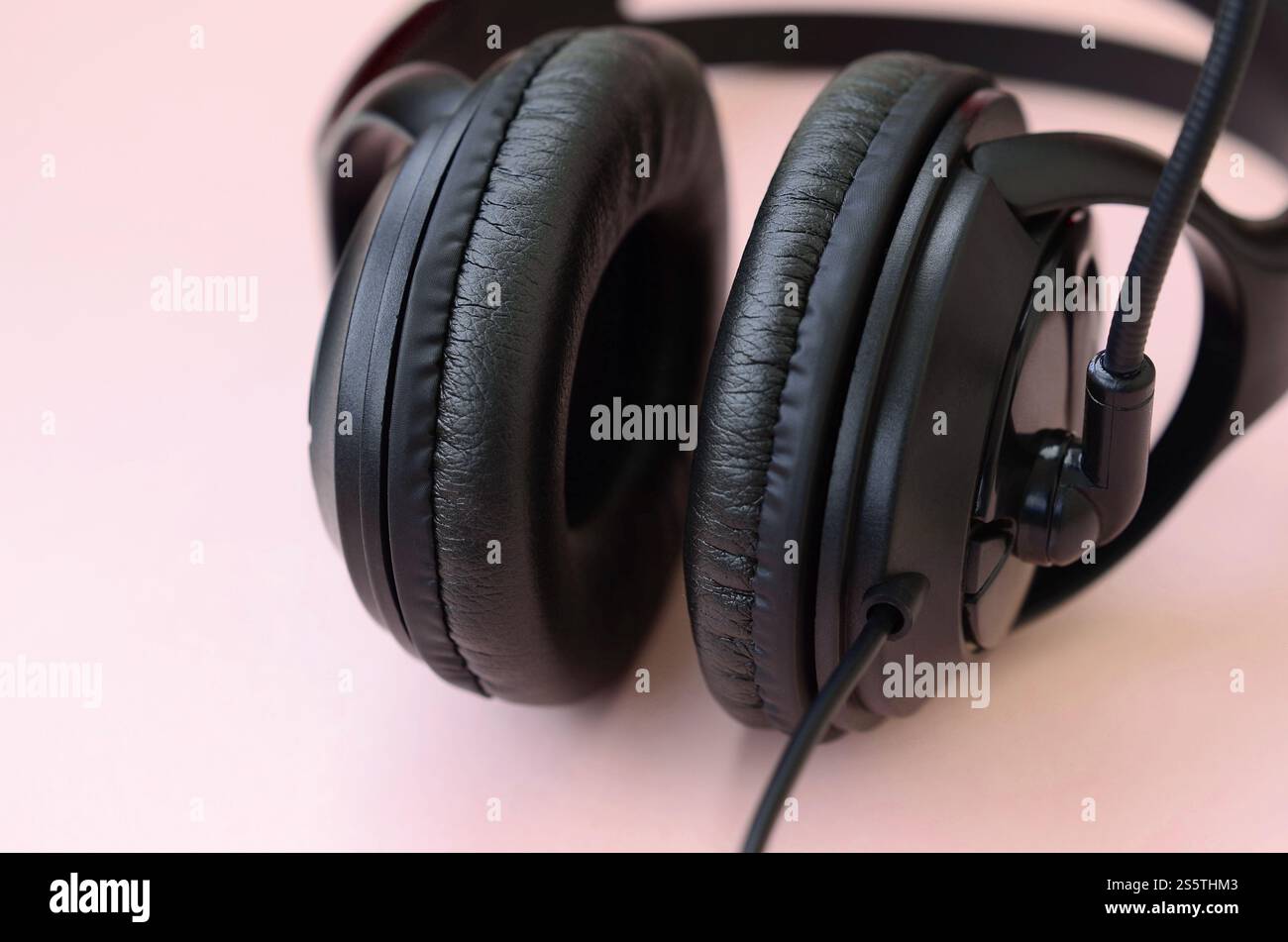 Le cuffie nere si trovano su un colorato sfondo rosa pastello. Concetto di ascolto musicale. Concetto di ascolto musicale. Le cuffie nere si trovano su sfondo rosa Foto Stock