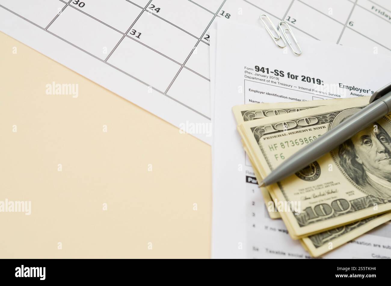 Modulo IRS 941-SS datori di lavoro dichiarazione dei redditi federale trimestrale in bianco si trova con penna e molte banconote da cento dollari sulla pagina del calendario. Concetto del periodo fiscale. Copia Foto Stock
