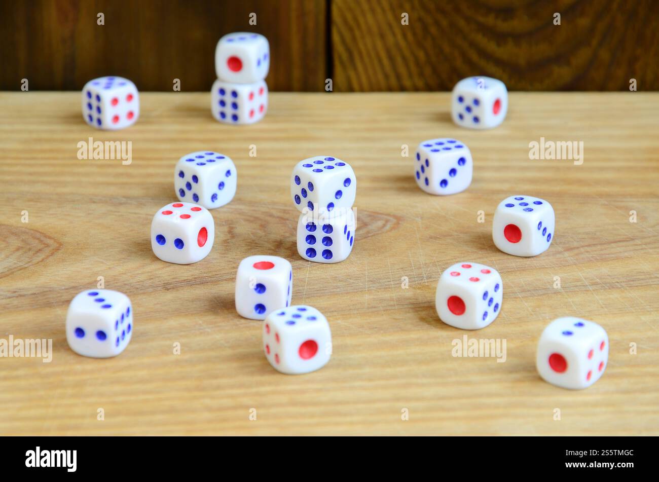 Alcuni dadi giacciono sulla superficie di legno naturale. Elementi per generare numeri da uno a sei sotto forma di punti dipinti sul lato di Foto Stock