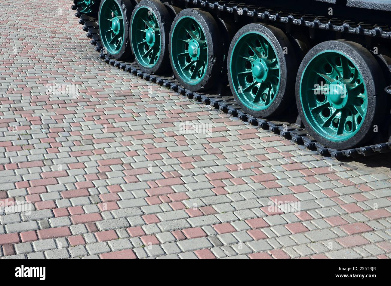 Un veicolo militare su cingoli sorge su un quadrato di pietre per pavimentazione. Foto di bruchi verde con ruote metalliche che li ruotano Foto Stock