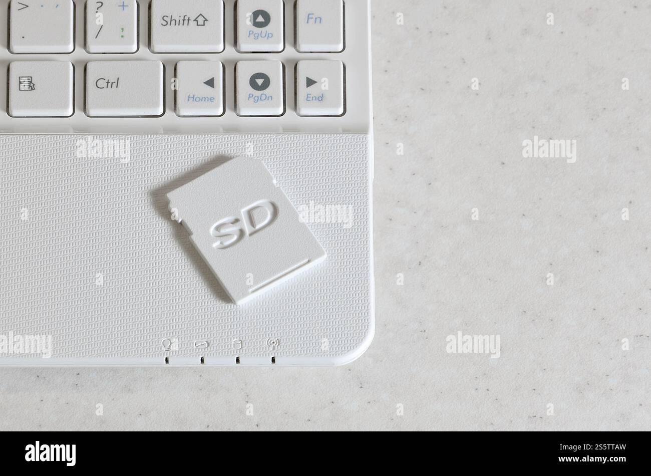 Una compatta scheda memoria SD giace su un netbook bianco. Le informazioni digitali il dispositivo di storage è pronto per l'uso. Concetto di moderne tecnologie Foto Stock