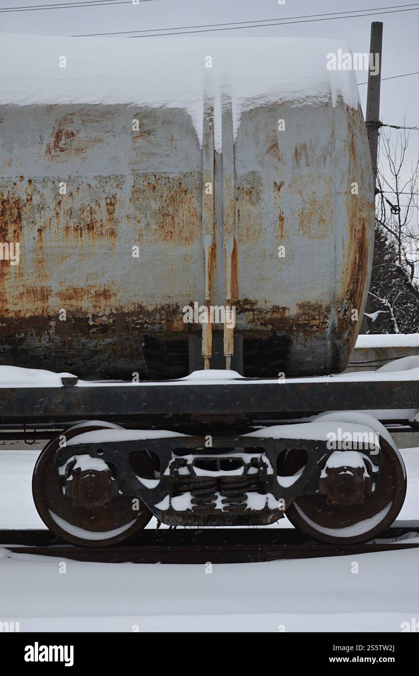 Foto dettagliata di un vagone ferroviario ghiacciato innevato. Un frammento dei componenti della vettura merci sulla ferrovia nelle nevose serali invernali. Foto Stock
