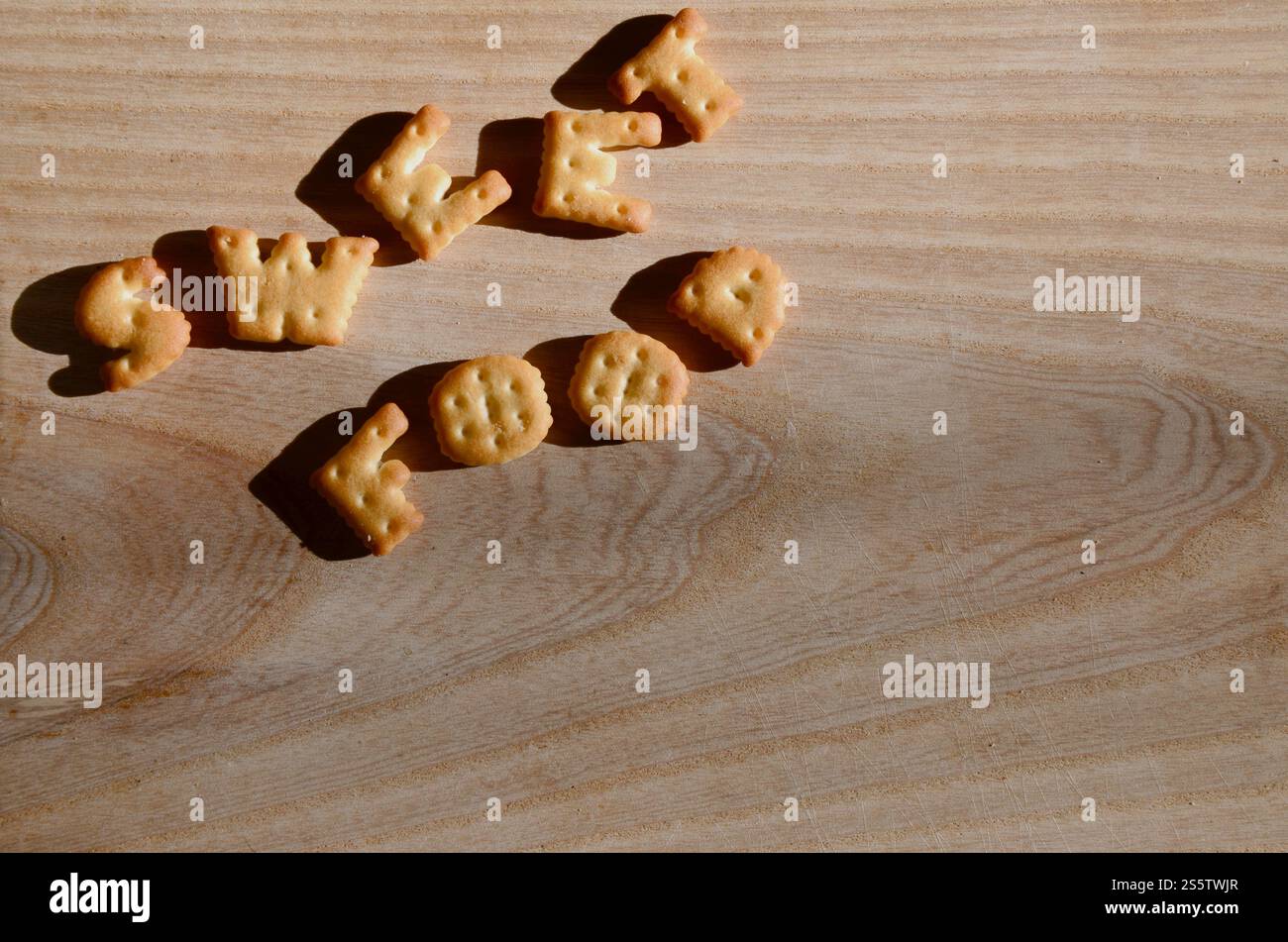 Cibo dolce. Testo dai cracker salati come lettere inglesi stampate che giacciono su un tagliere di legno. Messaggio, fiancheggiato da lettere commestibili. Dolce Foto Stock