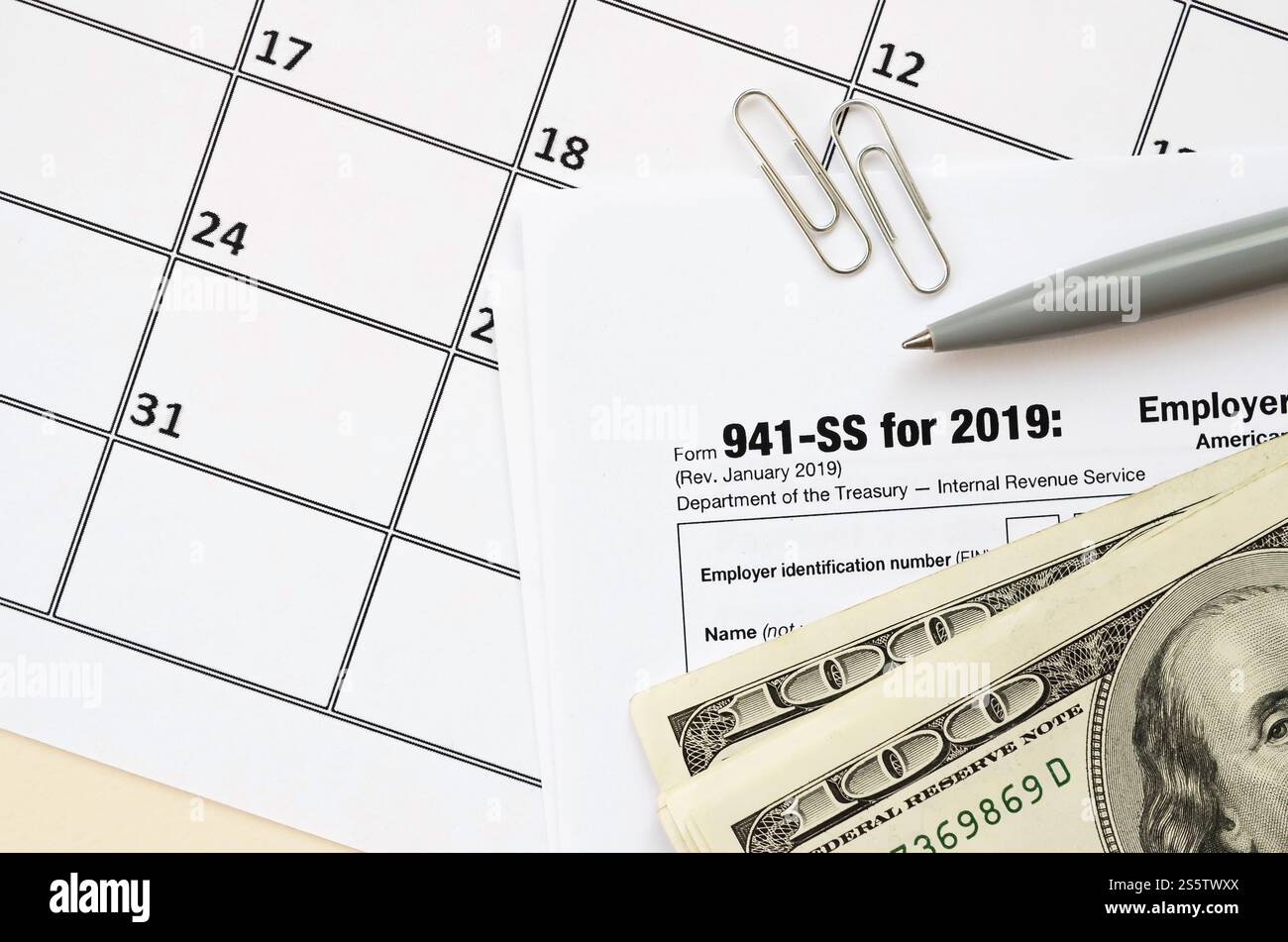 Modulo IRS 941-SS datori di lavoro dichiarazione dei redditi federale trimestrale in bianco si trova con penna e molte banconote da cento dollari sulla pagina del calendario. Concetto del periodo fiscale. Copia Foto Stock