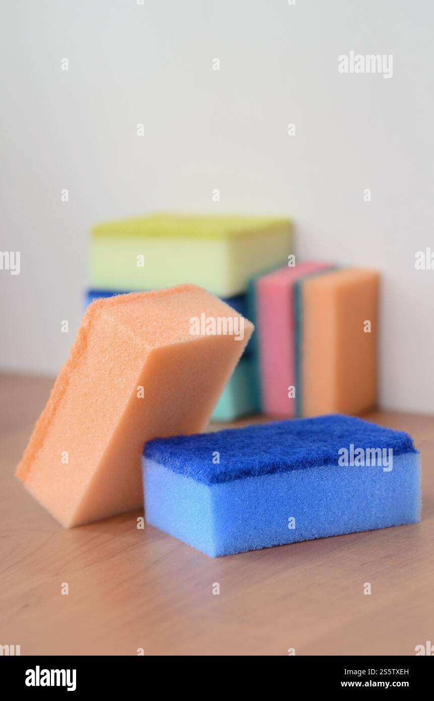 Un paio di spugne cucina giacciono su una cucina in legno il ripiano del bancone. Gli oggetti colorati per il lavaggio di stoviglie e pulizia in casa sono pronto per l'uso Foto Stock