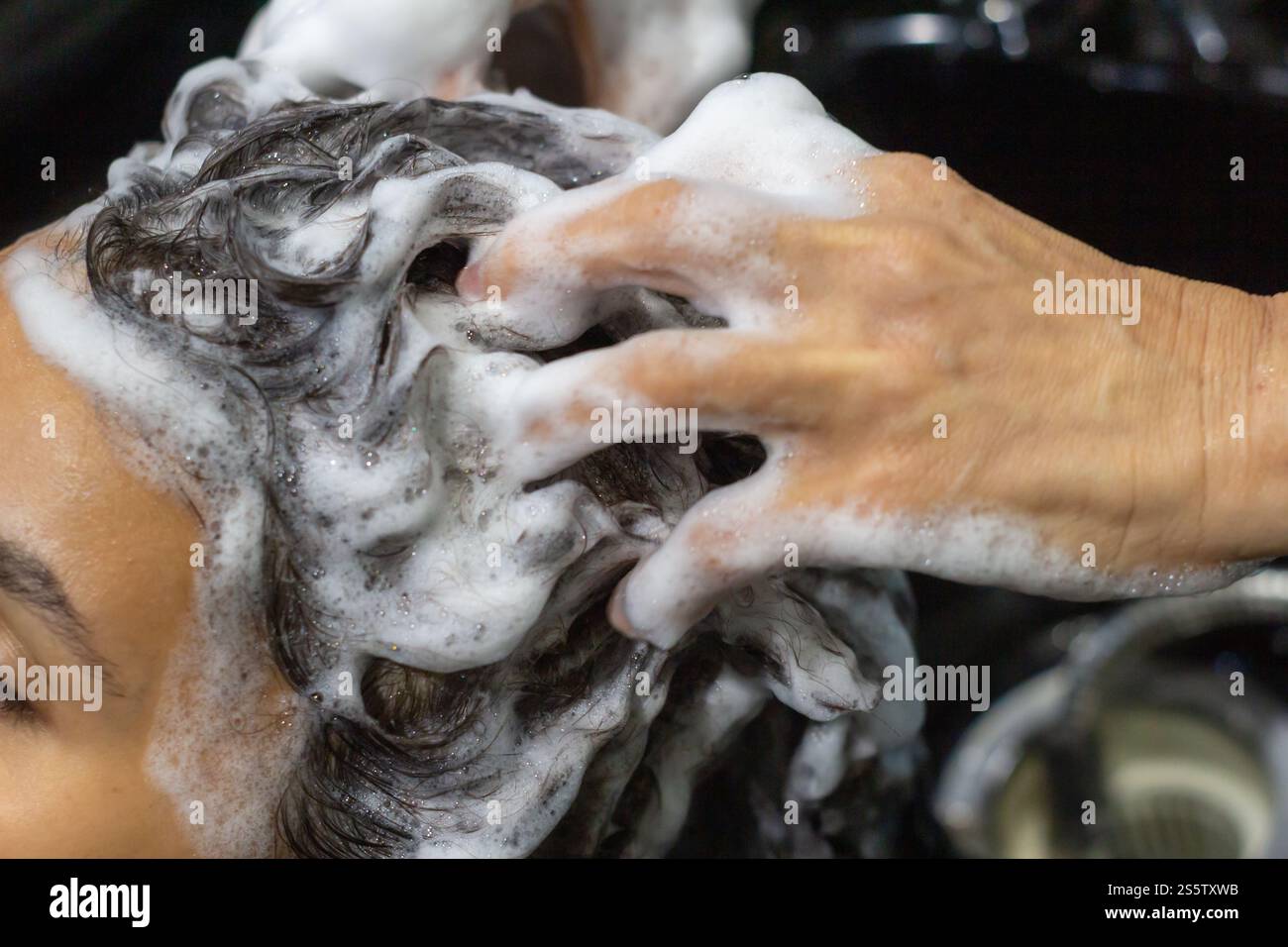 Bella giovane donna in salone che si lava i capelli con un concetto professionale, di stile di vita e di cura personale. Primo piano Foto Stock
