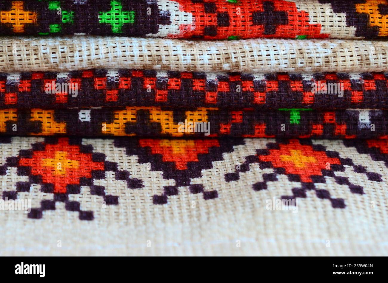 Pila di tradizionali disegni di arte popolare Ucraina lavorati a maglia su tessuto. Tela lavorata a maglia con design a pixel colorati. Una pila di tradizionali Foto Stock