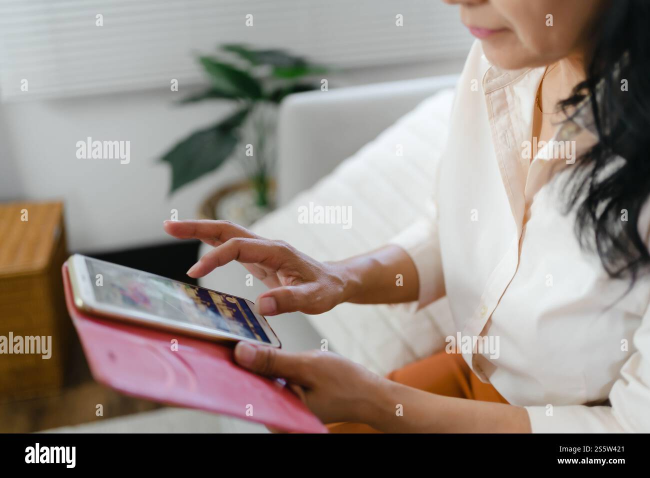 Donna asiatica di mezza età che tiene il telefono cellulare. donna anziana con smartphone. donna anziana che utilizza lo smartphone a casa con il concetto di tecnologia. Foto Stock