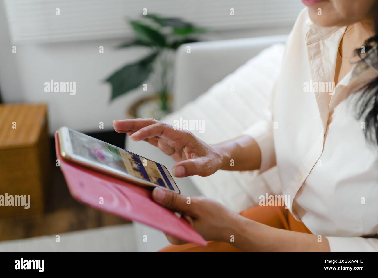 Donna asiatica di mezza età che tiene il telefono cellulare. donna anziana con smartphone. donna anziana che utilizza lo smartphone a casa con il concetto di tecnologia. Foto Stock