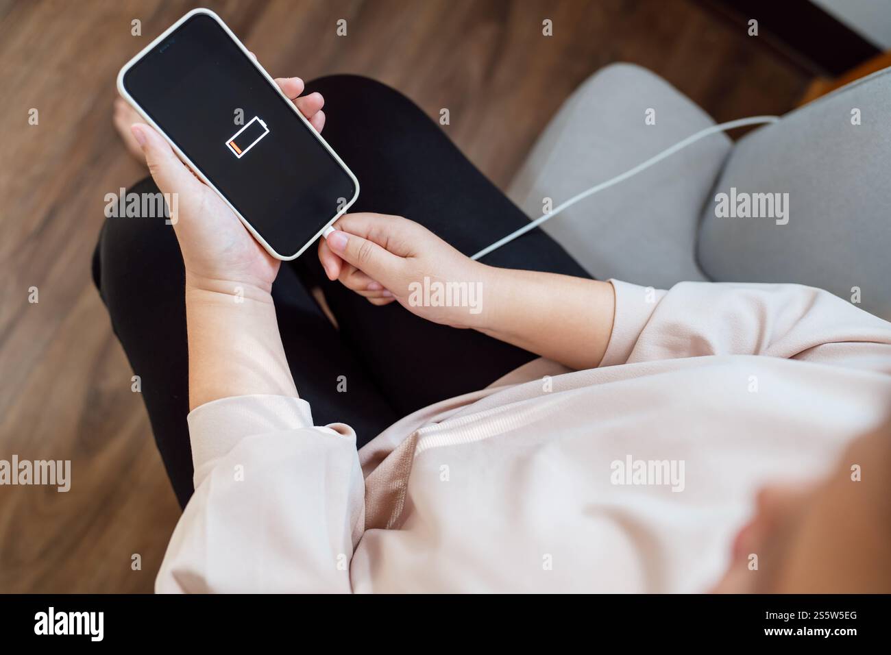 Donna che ricarica la batteria del telefono cellulare con batteria scarica. Collegare un caricabatterie a uno smartphone con un caricabatterie power Bank moderno Foto Stock