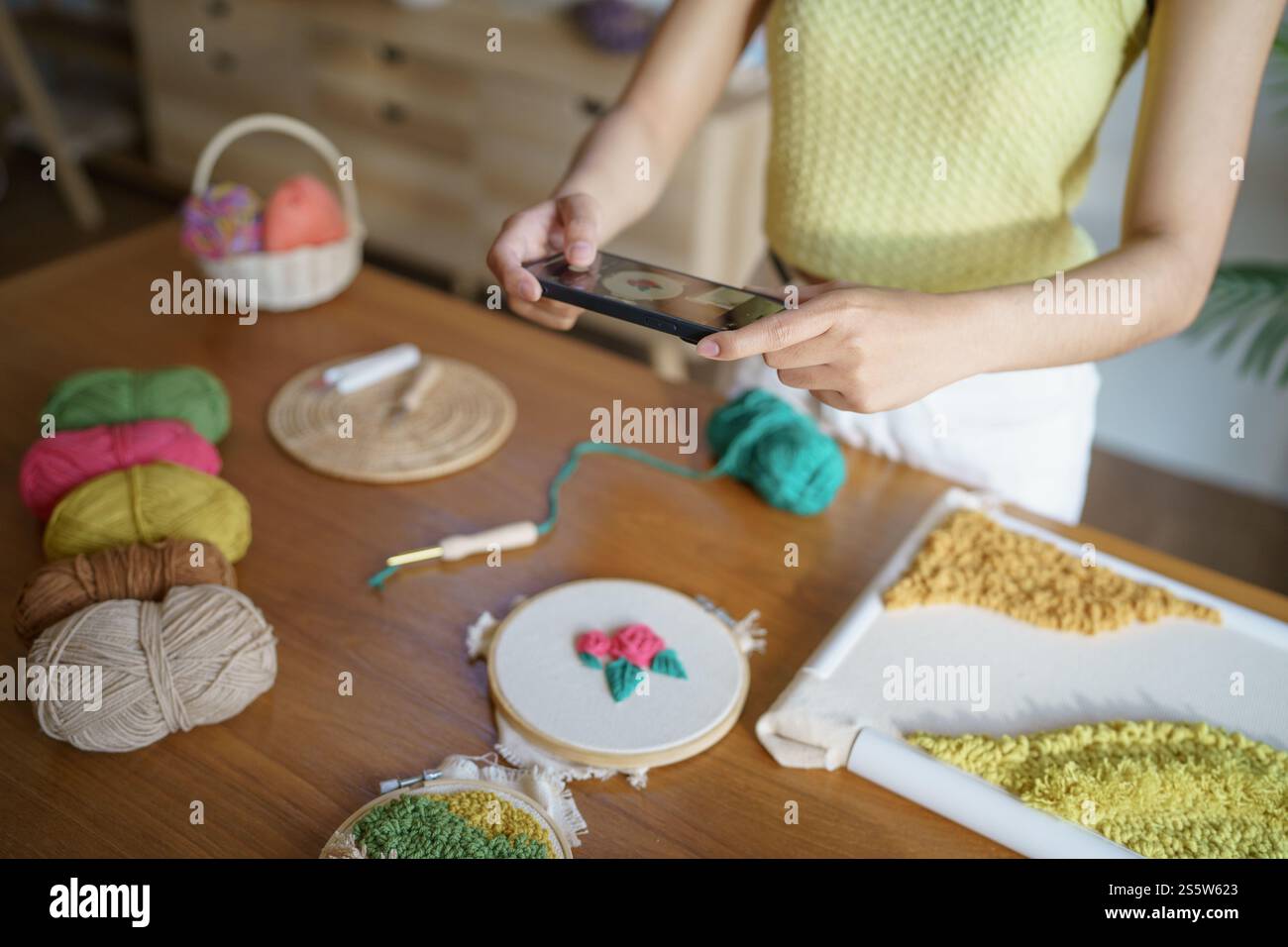 Donna asiatica che scatta foto smartphone Punch Needle. postazioni telefoniche sui social network in officina. Ambiente di lavoro di design progetto artigianale fai da te Foto Stock