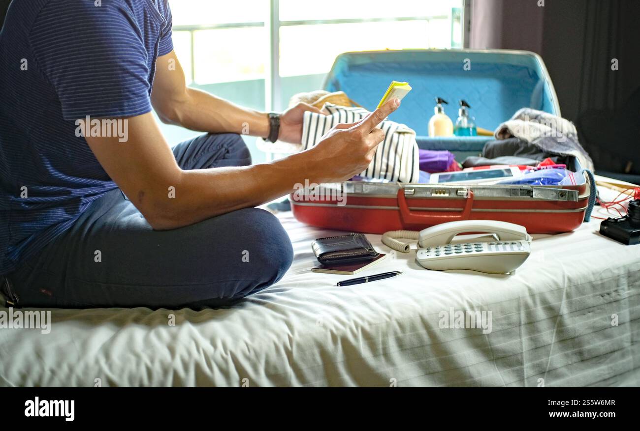 Uomo che prepara la lista dei bagagli per pianificare il viaggio, preparare le vacanze Prenota ora viaggiare trasporti Foto Stock
