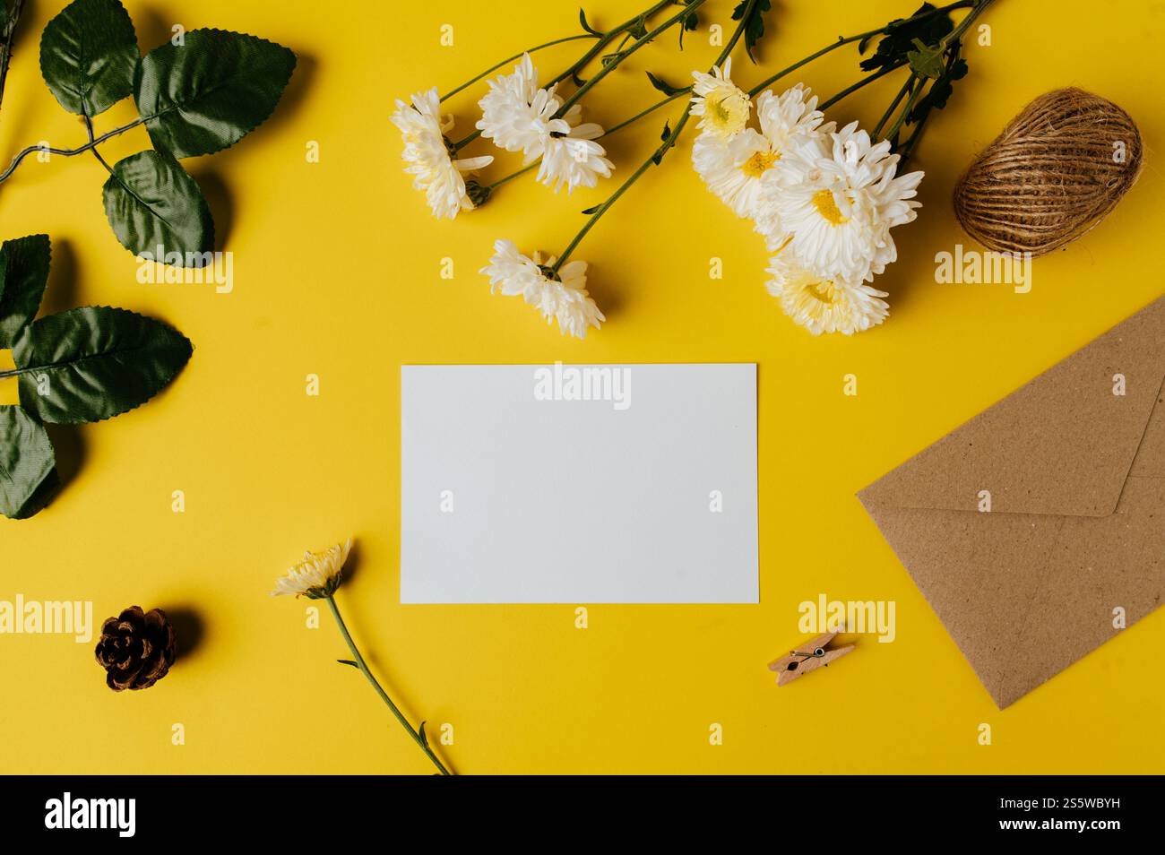 la carta bianca con la busta e il fiore è posta su sfondo giallo Foto Stock
