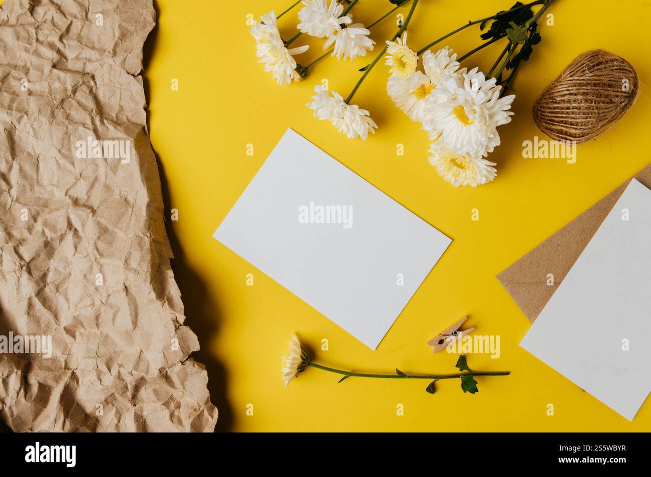 la carta bianca con la busta e il fiore è posta su sfondo giallo Foto Stock