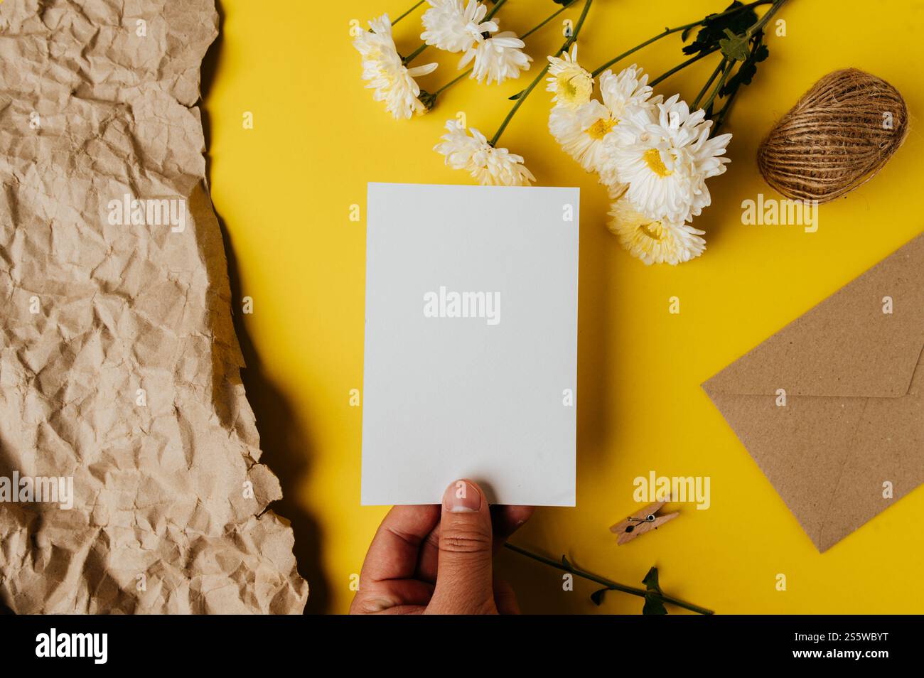 la carta bianca con la busta e il fiore è posta su sfondo giallo Foto Stock