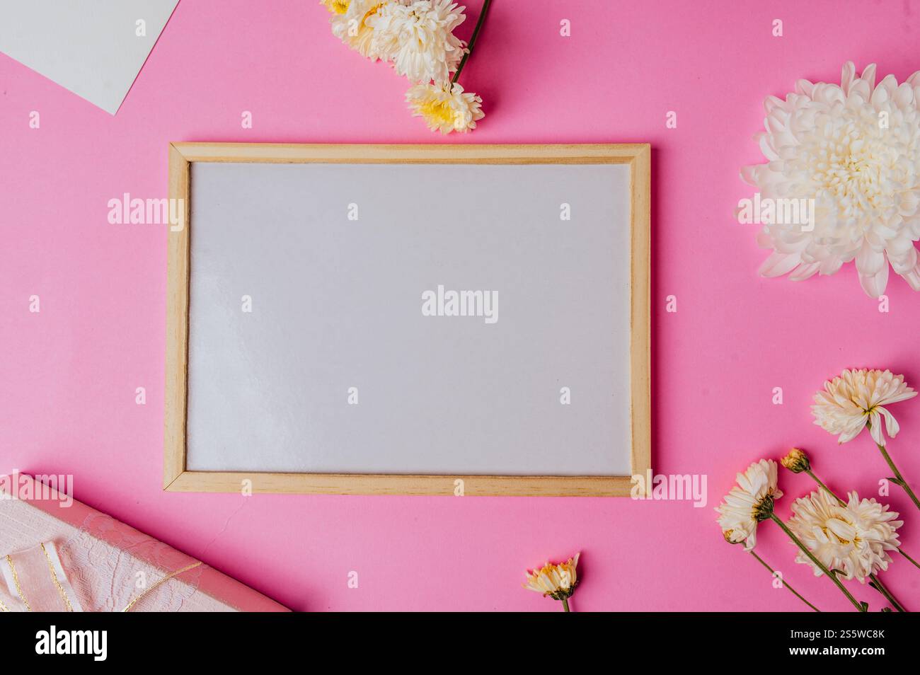 lavagna bianca con fiore su sfondo rosa Foto Stock