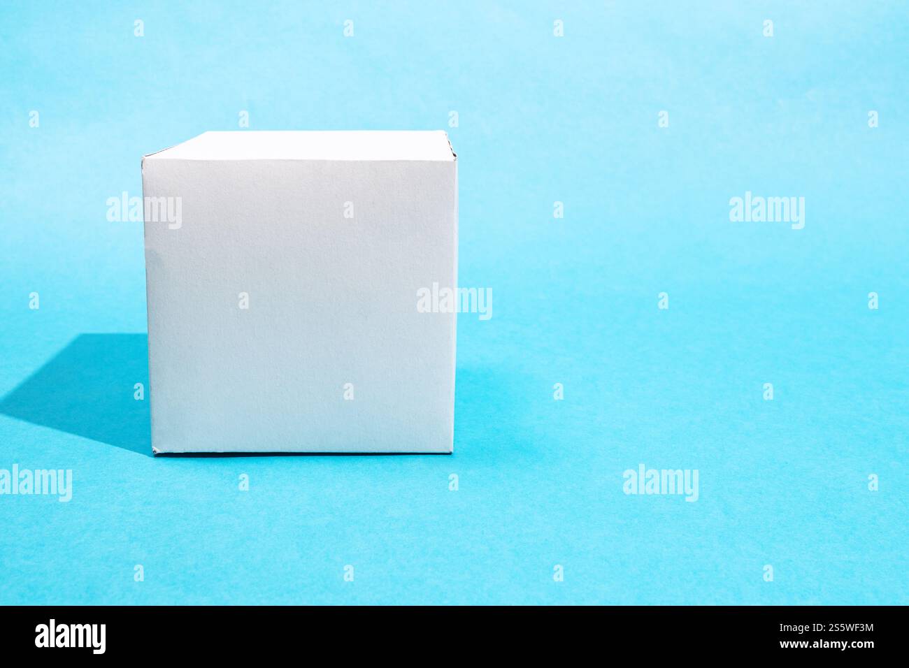 vista frontale del cubo di carta realizzato a mano su sfondo blu turchese con spazio copiato Foto Stock