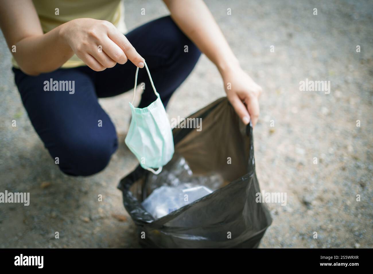 Donna volontaria di beneficenza che tiene la maschera chirurgica protettiva durante la pandemia di coronavirus. COVID-19. gettare via la maschera protettiva usata in Foto Stock