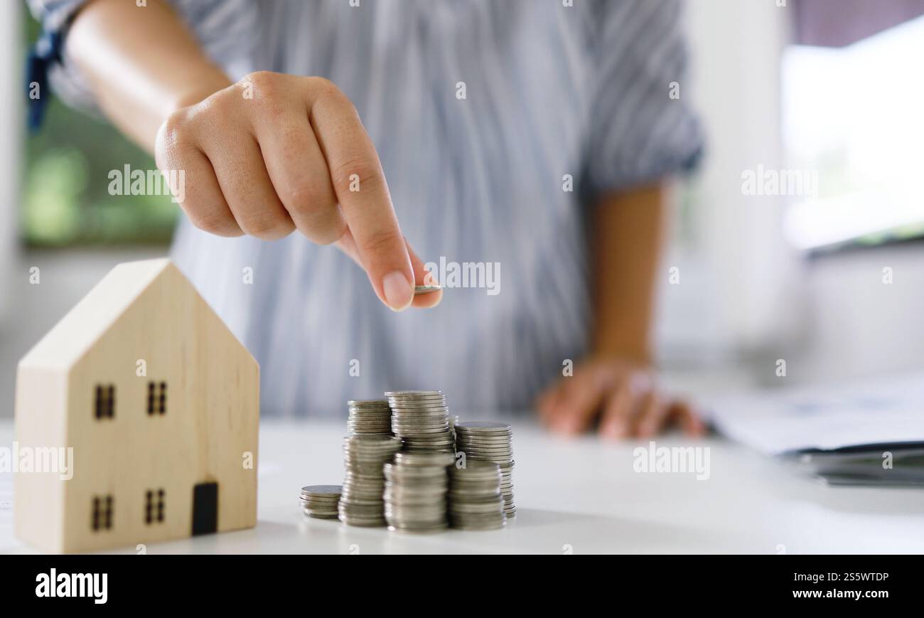 Risparmio di denaro per gli investimenti immobiliari con una pila di monete per l'acquisto di una casa e prestito per la preparazione della futura assicurazione finanziaria Foto Stock