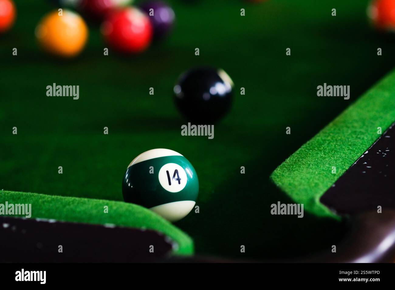 Mans mano e braccio cue giocano a biliardo o si preparano a sparare palle da biliardo su un tavolo da biliardo verde. Palline da biliardo colorate sul fregio verde Foto Stock
