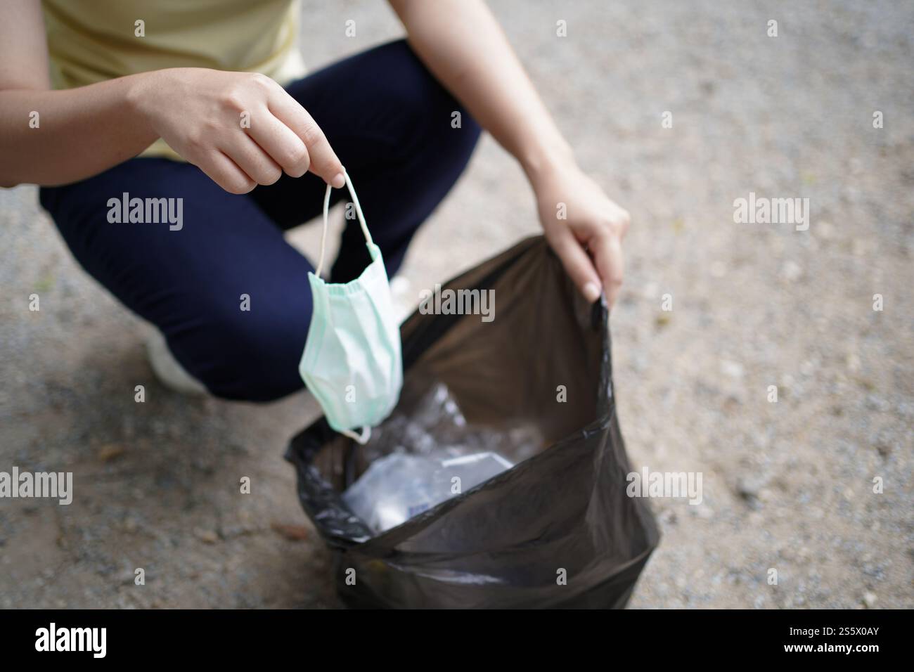 Donna volontaria di beneficenza che tiene la maschera chirurgica protettiva durante la pandemia di coronavirus. COVID-19. gettare via la maschera protettiva usata in Foto Stock