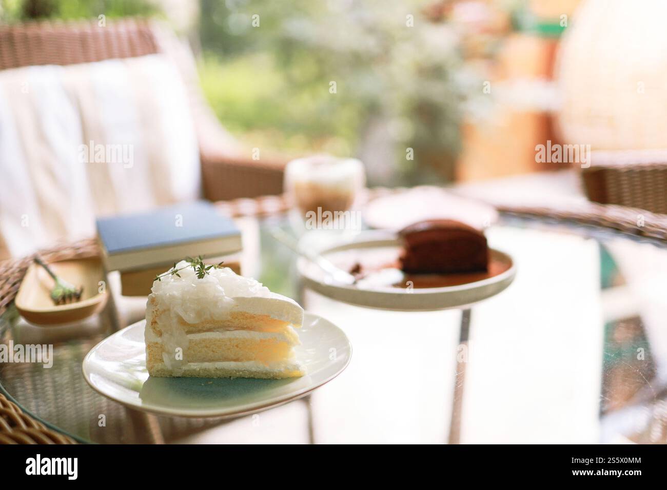 Torta al cocco e caffè in una caffetteria sullo sfondo sfocato. Dessert tradizionale a fette di deliziosa torta a strati di cocco. Foto Stock
