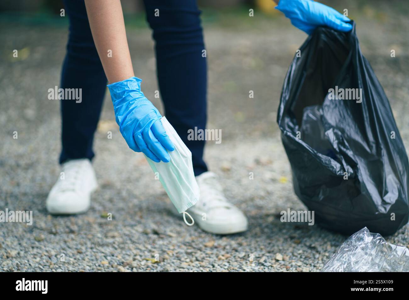 Donna volontaria di beneficenza che tiene la maschera chirurgica protettiva durante la pandemia di coronavirus. COVID-19. gettare via la maschera protettiva usata in Foto Stock