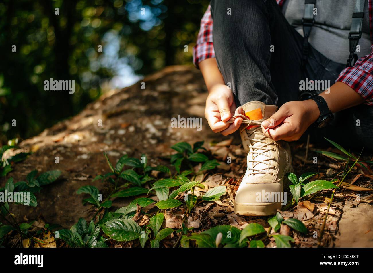 Primo piano, mano di un giovane seduto e legando lacci delle scarpe durante le camminate sul sentiero, spazio copia Foto Stock