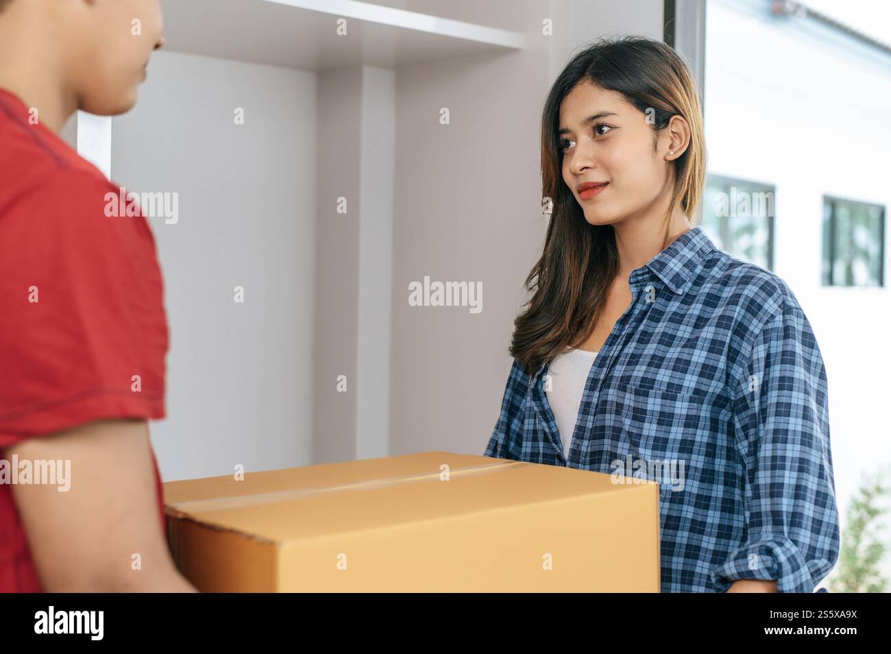 La giovane coppia asiatica aiuta a tenere una pesante scatola di cartone entra in una nuova casa con felicità, nuovo concetto di casa in movimento Foto Stock
