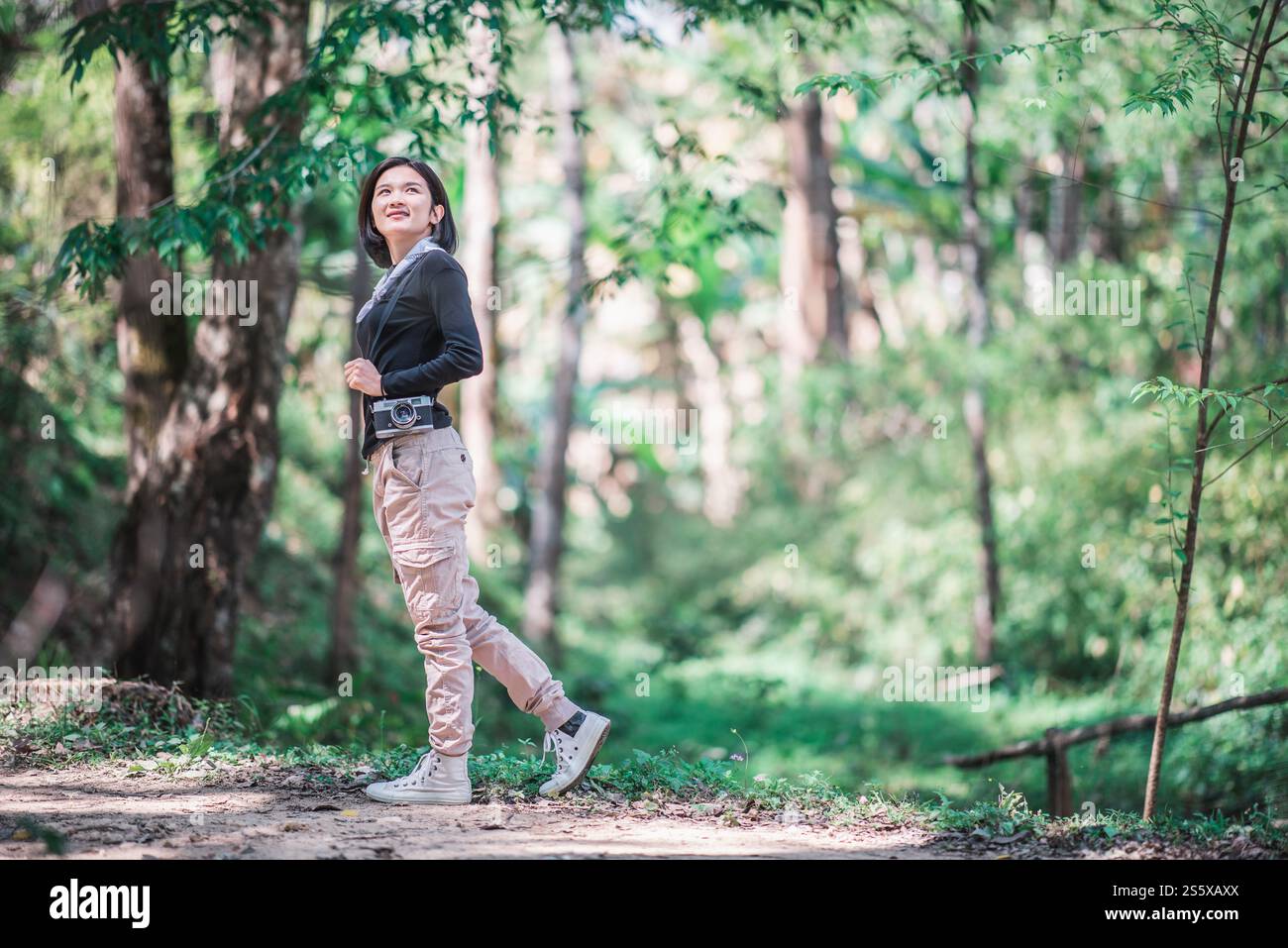 La giovane bella donna usa la fotocamera digitale per scattare una foto della splendida natura mentre campeggia nella foresta con felicità, copia spazio Foto Stock