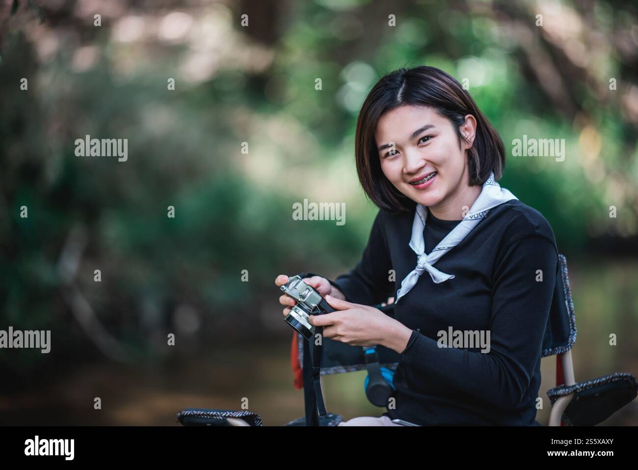 La giovane bella donna usa la fotocamera digitale per scattare una foto della splendida natura mentre campeggia nella foresta con felicità, copia spazio Foto Stock