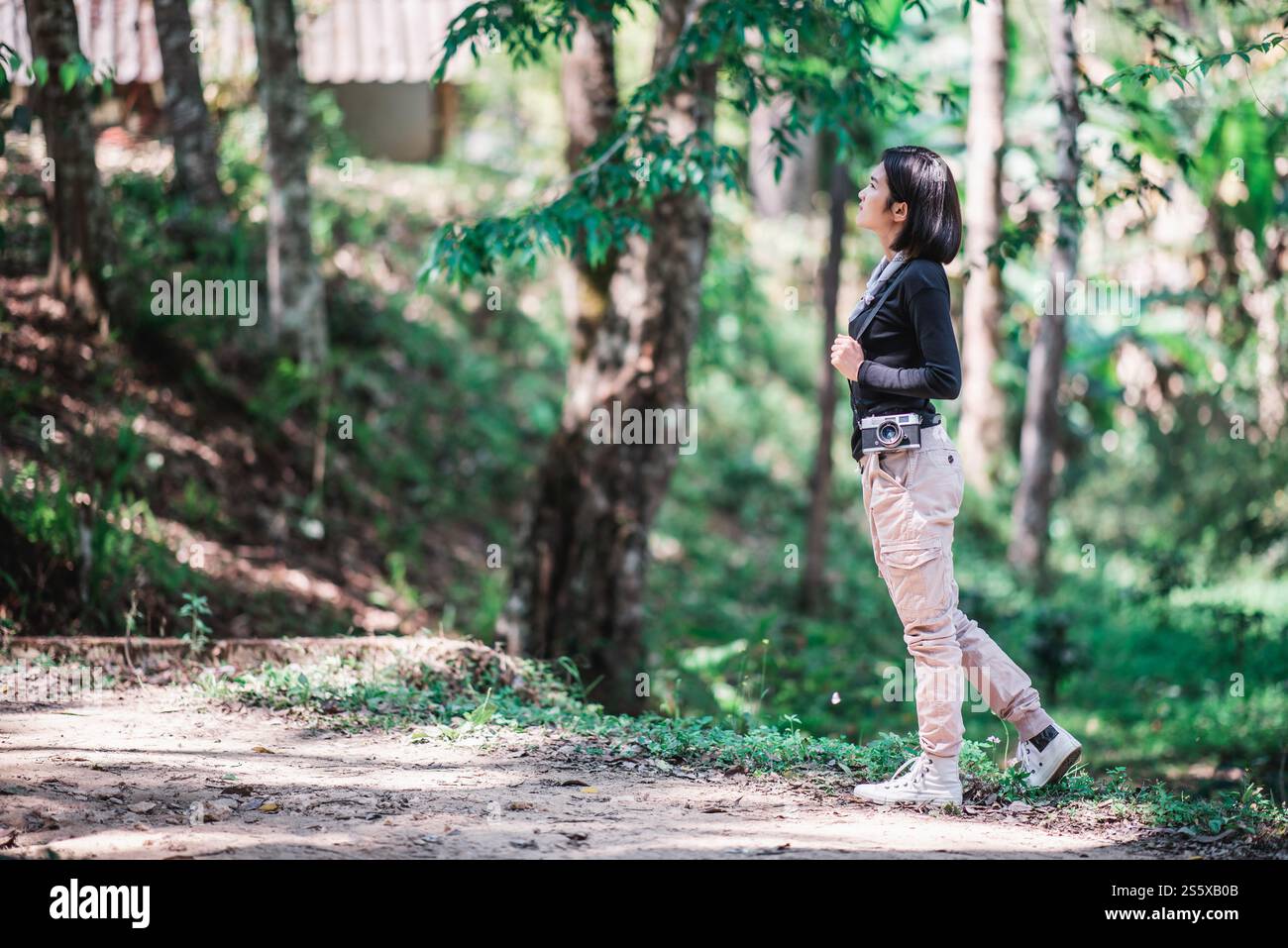 La giovane bella donna usa la fotocamera digitale per scattare una foto della splendida natura mentre campeggia nella foresta con felicità, copia spazio Foto Stock