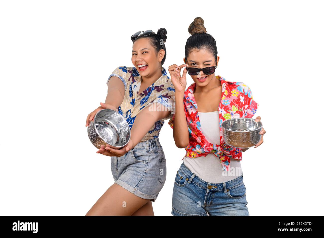 Ritratti due donne in camicia floreale e jeans corti con ciotola d'acqua, sorridendo con allegria su sfondo bianco, amici felici con il festival di Songkran, T Foto Stock