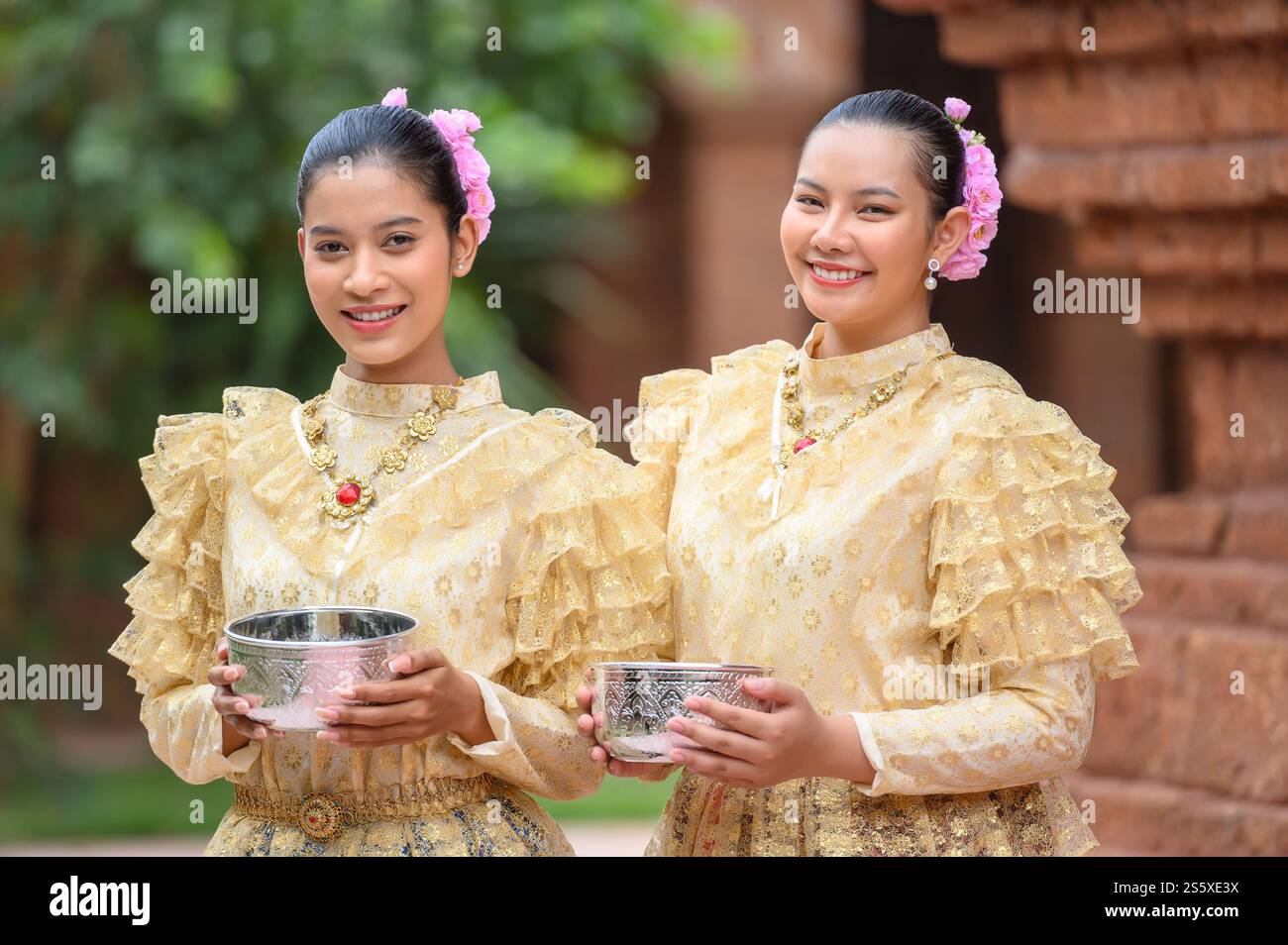Ritratti due belle donne al festival di Songkran con costume tradizionale tailandese nel tempio che regge ciotola d'acqua e sorriso. Cultura thailandese con Foto Stock
